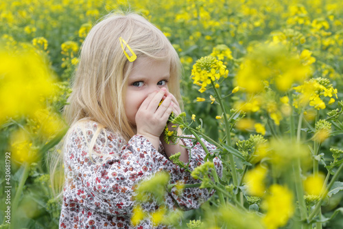Outdoor candid portrait of cute blonde girl in field of yellow flowers. © triocean