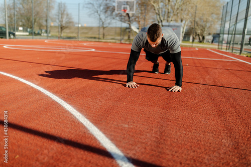 Photo of a young athletic man doing push ups outdoors.