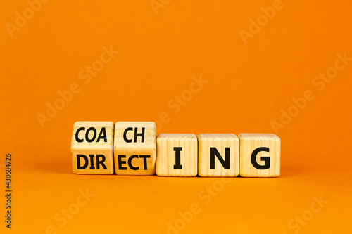 Coaching or directing leadership style symbol. Turned cubes and changed words 'directing' to 'coaching'. Beautiful orange background, copy space. Business, coaching or directing concept.