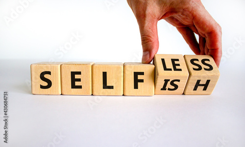 Selfish or selfless symbol. Businessman turns cubes and changes the word 'selfish' to 'selfless'. Beautiful white background, copy space. Business, psuchological and selfish or selfless concept. photo