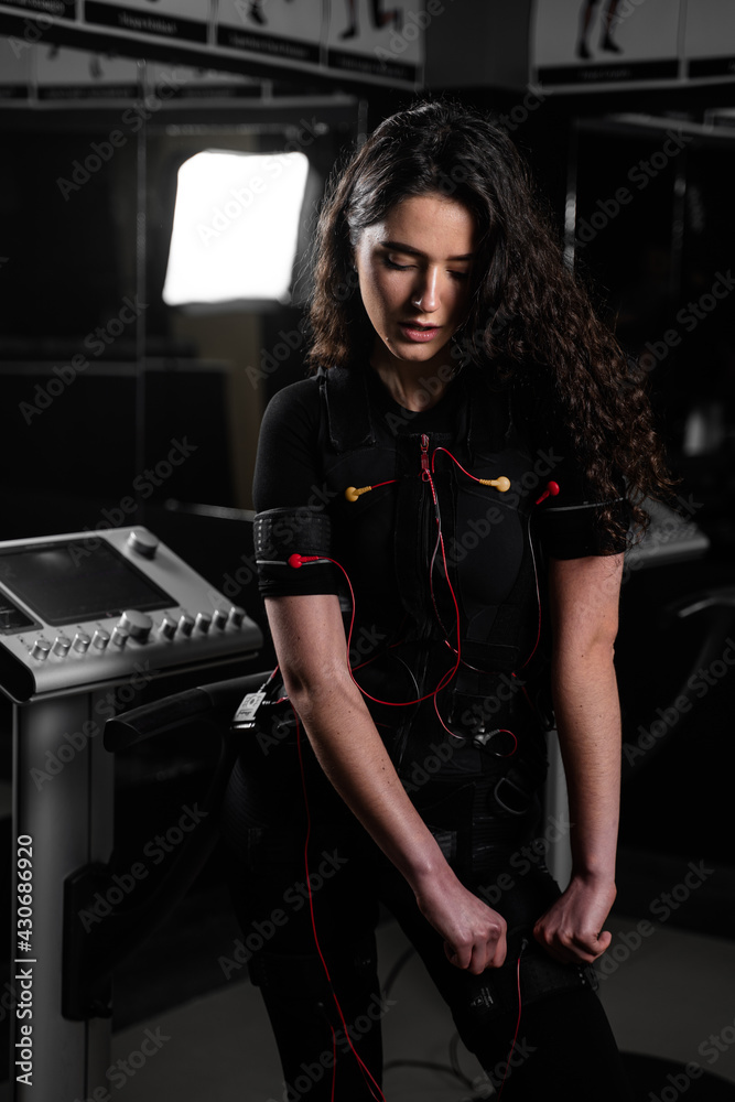 Girl in EMS suit in gym. Sport training in electrical muscle stimulation suit. Making physical exercises Girl in EMS suit in gym. Sport training in electrical muscle stimulation suit. Making physical exercises