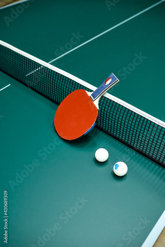 a red pinpong racket with two balls lies on a tennis table