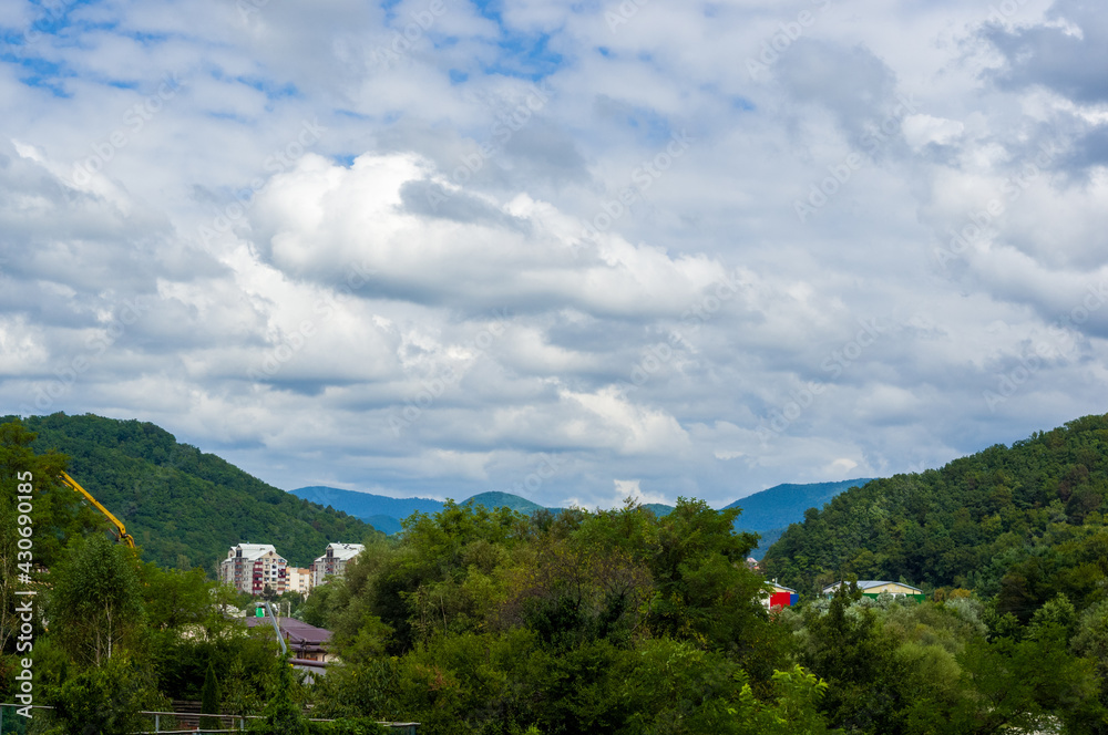 Fototapeta premium Resort village in mountain valley against the blue sky with clouds, summer landscape