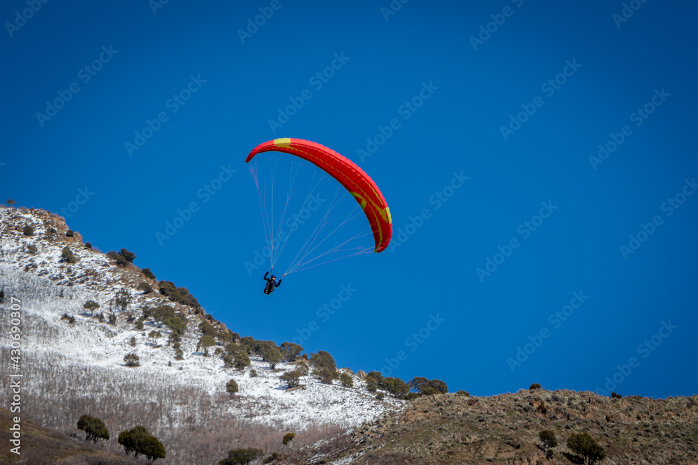 Paraglider With Red Parachute Wing Flying in a Blue Sky With Clouds Paraglider With Red Parachute Wing Flying in a Blue Sky With Clouds