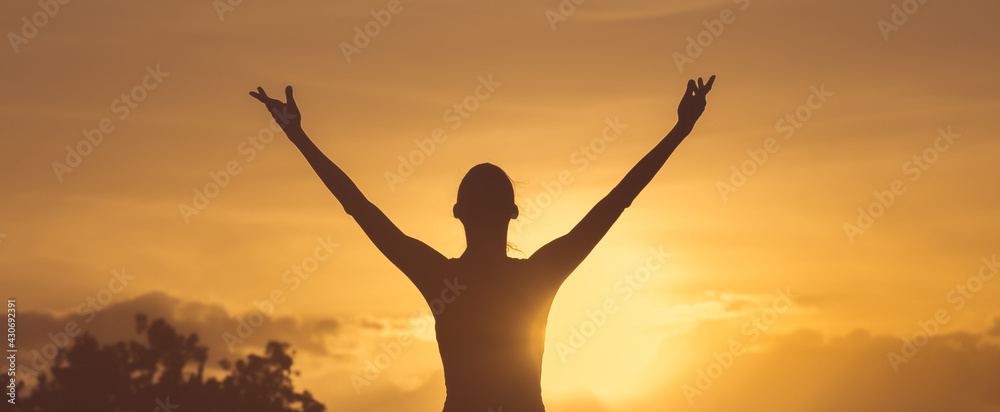Happy woman with hands up to the sunset sky. Positive energy, prayer and gratitude concept.	