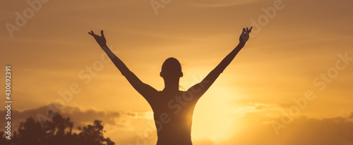 Happy woman with hands up to the sunset sky. Positive energy, prayer and gratitude concept. 