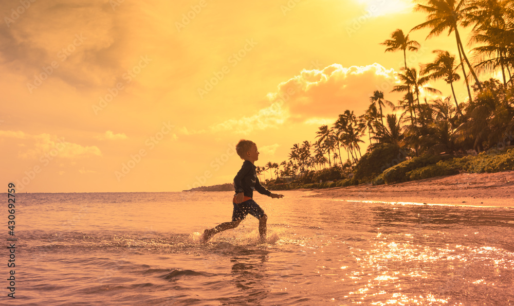 Happy child running having fun on the beach at sunset. Summer fun holiday concept. 