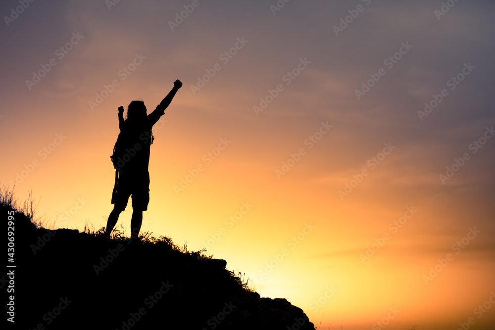 silhouette of a motivated person on the top of mountain celebrating with fist up to the sky. silhouette of a motivated person on the top of mountain celebrating with fist up to the sky.
