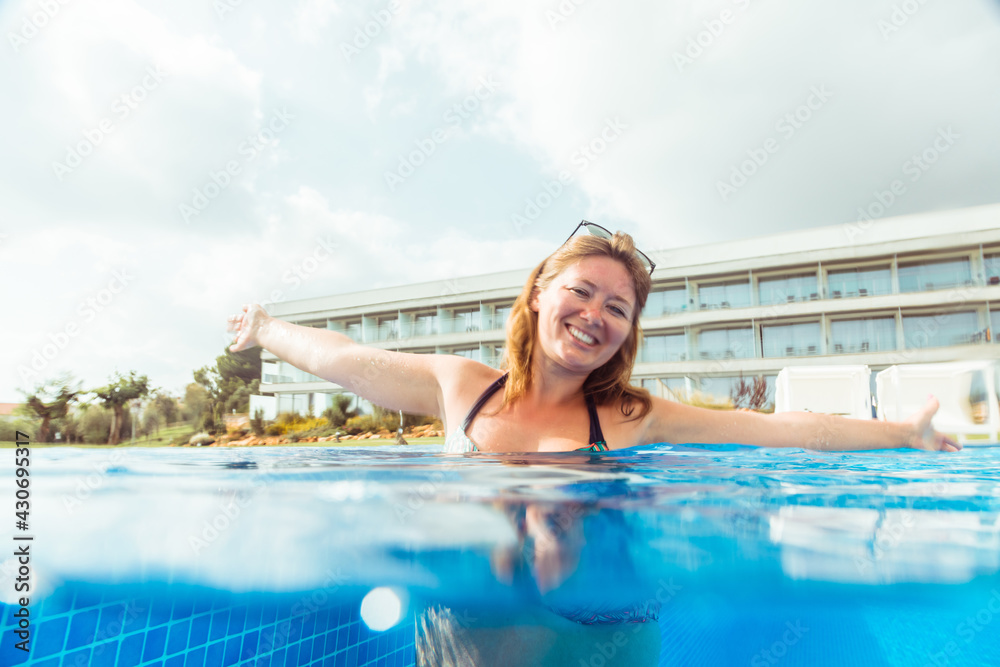 attractive smiling woman in bikini relaxing in swimming pool and enjoying summer vacation