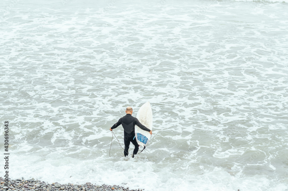 Portrait of mature surfer standing on the beach with a surfboard in hands. Portrait of mature surfer standing on the beach with a surfboard in hands.
