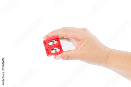 woman's hand holding red pencil sharpener on white background
