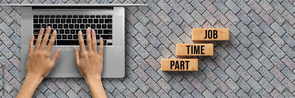 hand over a computer and cubes with message PART TIME JOB on stone pavement background hand over a computer and cubes with message PART TIME JOB on stone pavement background