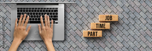 Fotografie hand over a computer and cubes with message PART TIME JOB on stone pavement back