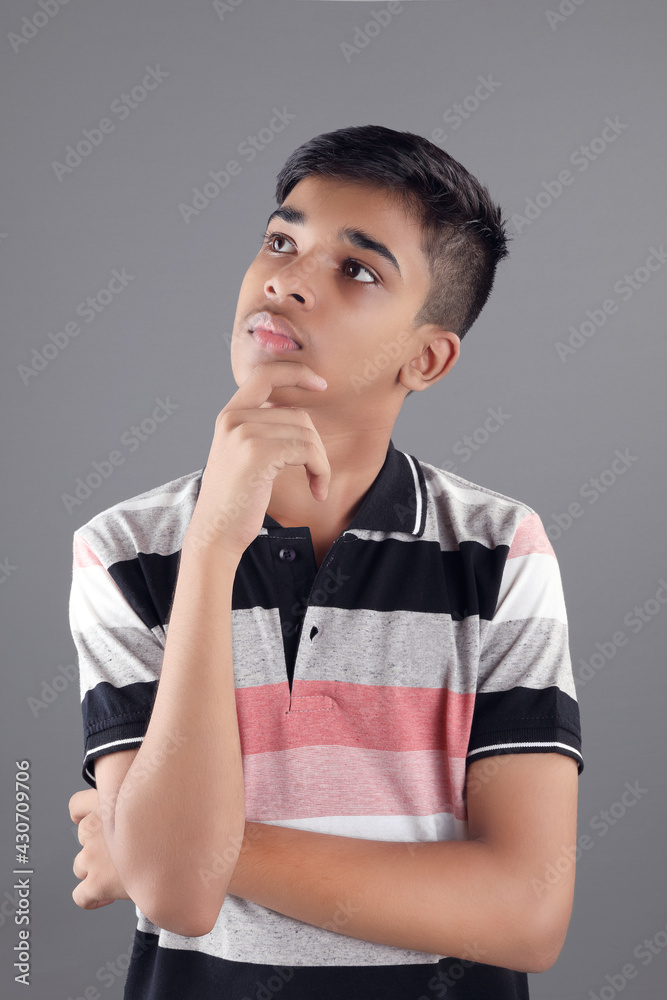Thoughtful Indian teenage boy on grey background Thoughtful Indian teenage boy on grey background