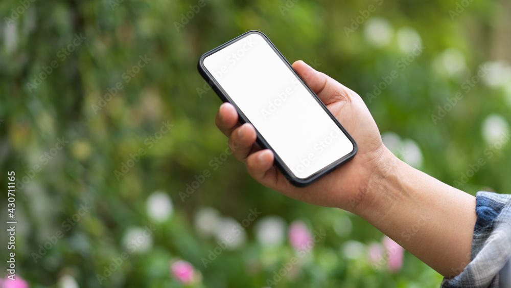 Male holding smartphone include clipping path screen in blurred garden background