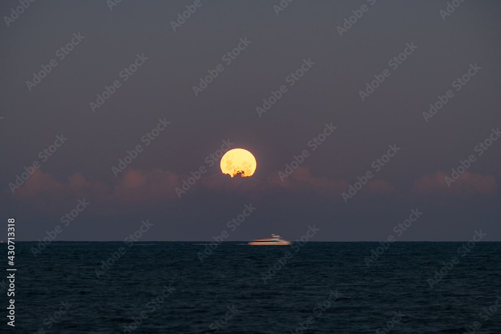 Full moon rising over the sea and cloud bank