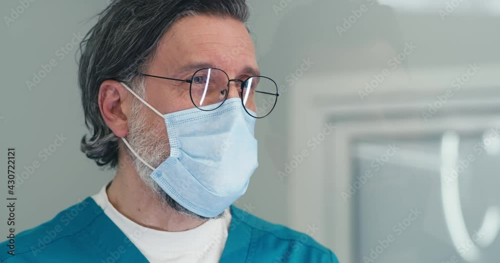 Mature doctor in mask speaking with patient on reception in medical center Mature doctor in mask speaking with patient on reception in medical center