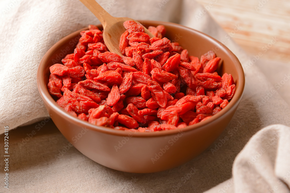 Bowl with dried goji berries on light wooden background Bowl with dried goji berries on light wooden background