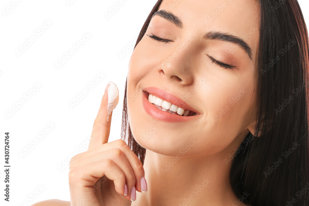 Beautiful woman applying facial cream on white background, closeup
