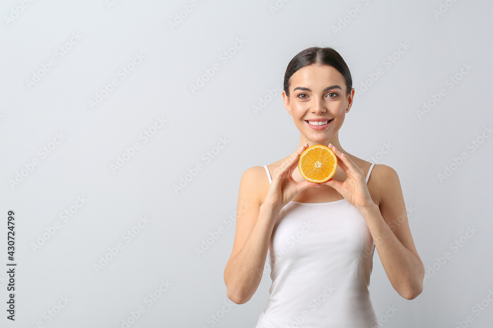 Beautiful young woman with orange on light background Beautiful young woman with orange on light background