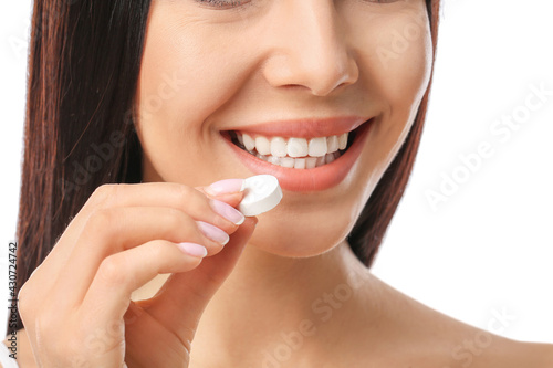 Beautiful woman taking vitamin C pill on white background  closeup
