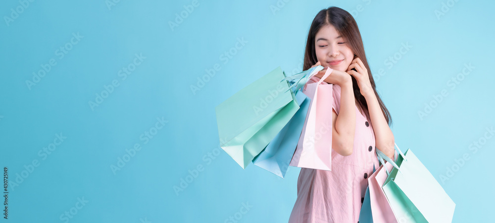 portrait of cheerful young brunette woman holding credit card and shopping bags over Blue background. shopaholic Concept - obrazy, fototapety, plakaty 