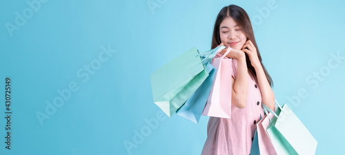 portrait of cheerful young brunette woman holding credit card and shopping bags over Blue background. shopaholic Concept photo