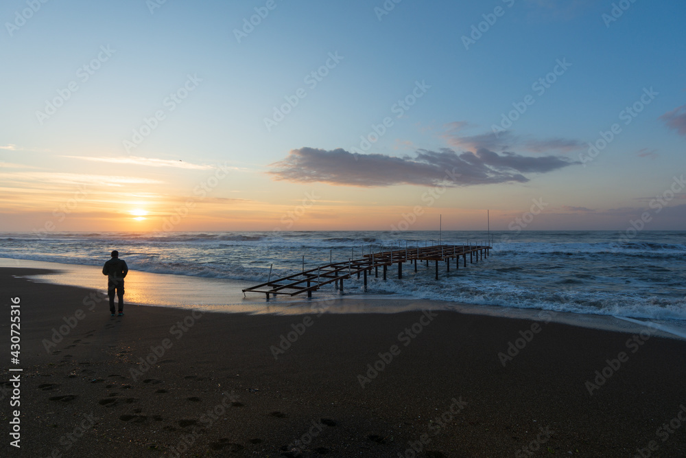 A man standing on the beach during sunrise