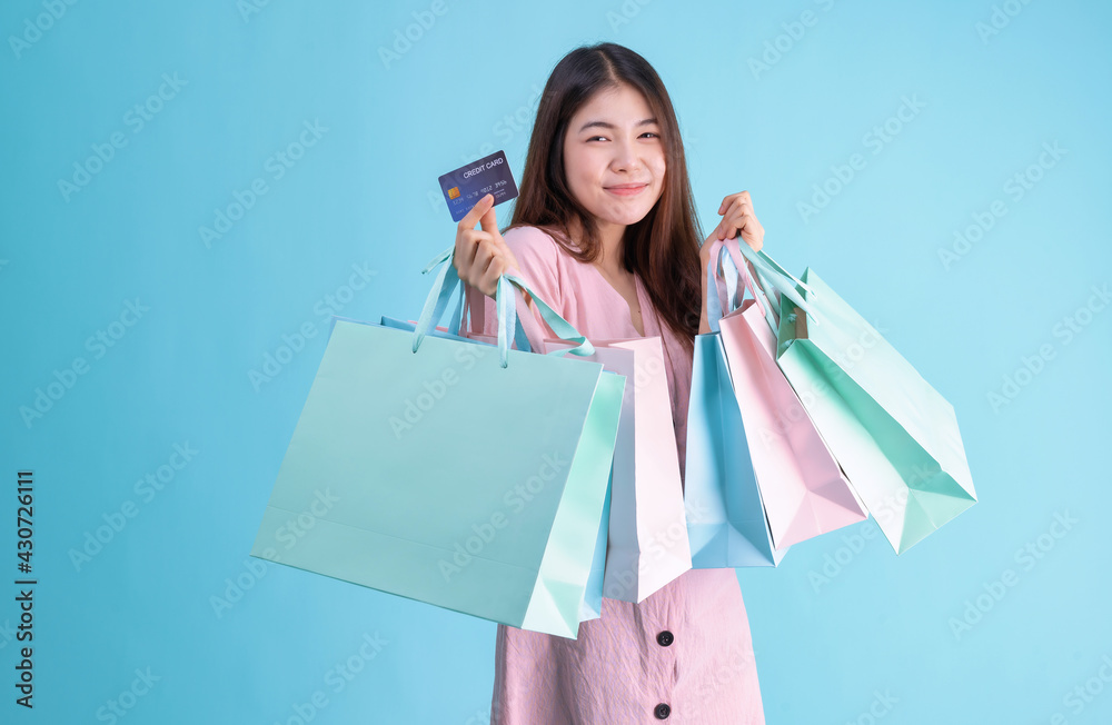 portrait of cheerful young brunette woman holding credit card and shopping bags over Blue background. shopaholic Concept portrait of cheerful young brunette woman holding credit card and shopping bags over Blue background. shopaholic Concept