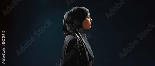 Profile of young arabian woman in hijab standing sideways
