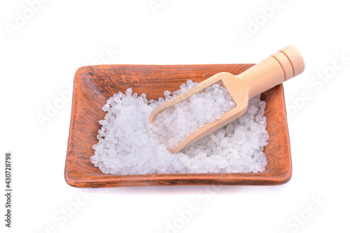 Sea salt in a salt shaker with a wooden ladle isolated on a white background.