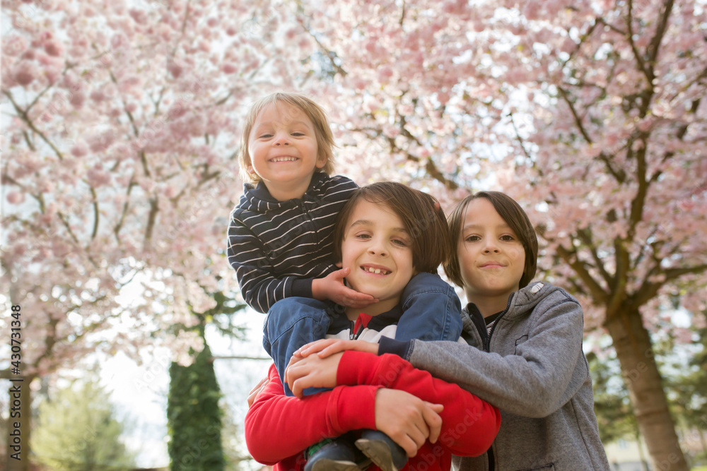 Happy children, siblings in pink blooming sacura garden, playing Happy children, siblings in pink blooming sacura garden, playing