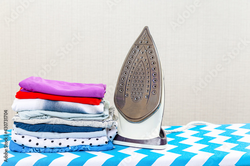 Stack of colorful cotton clothes and iron.Household laundry ironing.