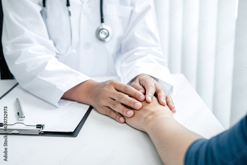 Doctor holding hands on patient about bad news at consulting room Doctor holding hands on patient about bad news at consulting room