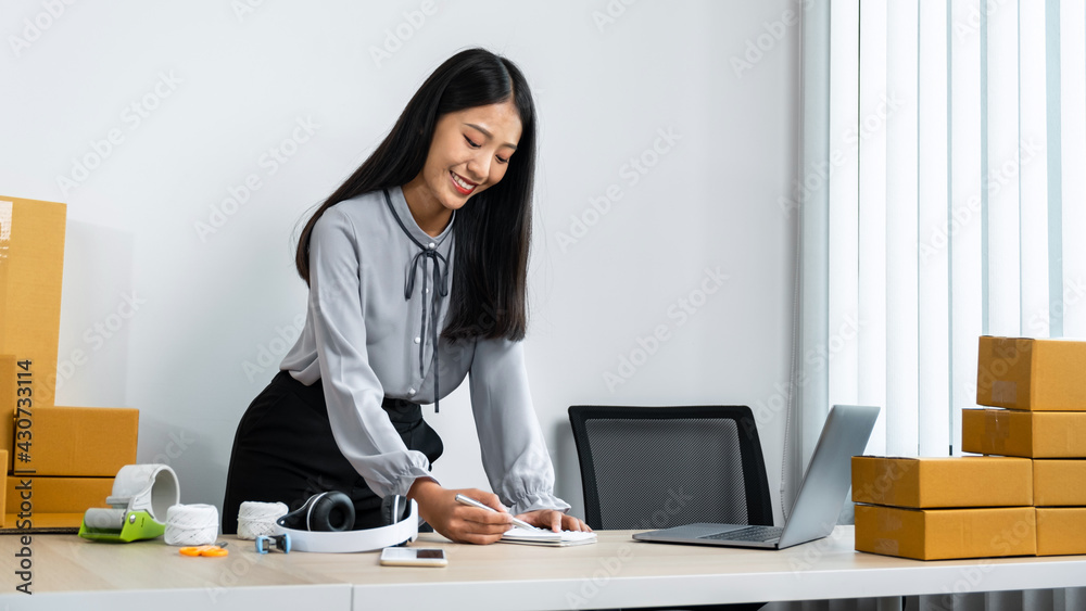 Young business woman entrepreneur smiling and writing order on notebook