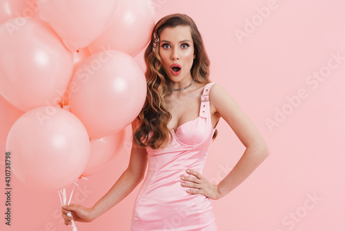 Young shocked woman wearing dress posing with balloons