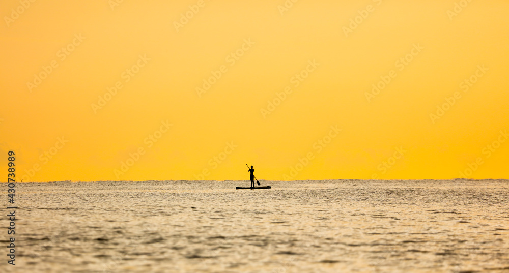 Fototapeta premium A girl on a board with an oar floats on the sea
