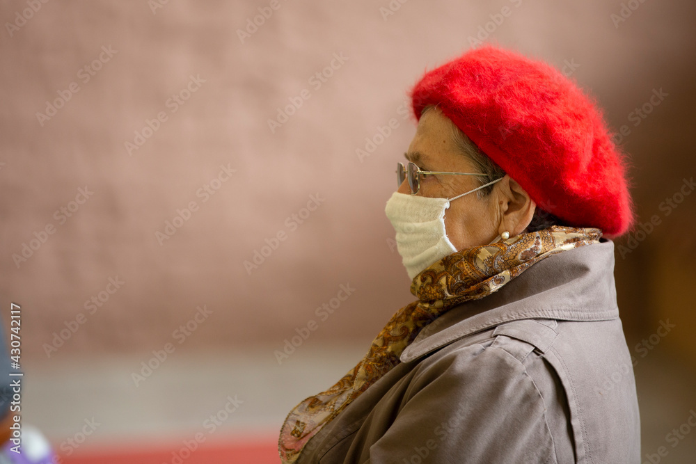  An elderly woman in a medical mask at an event during a coronavirus infection.