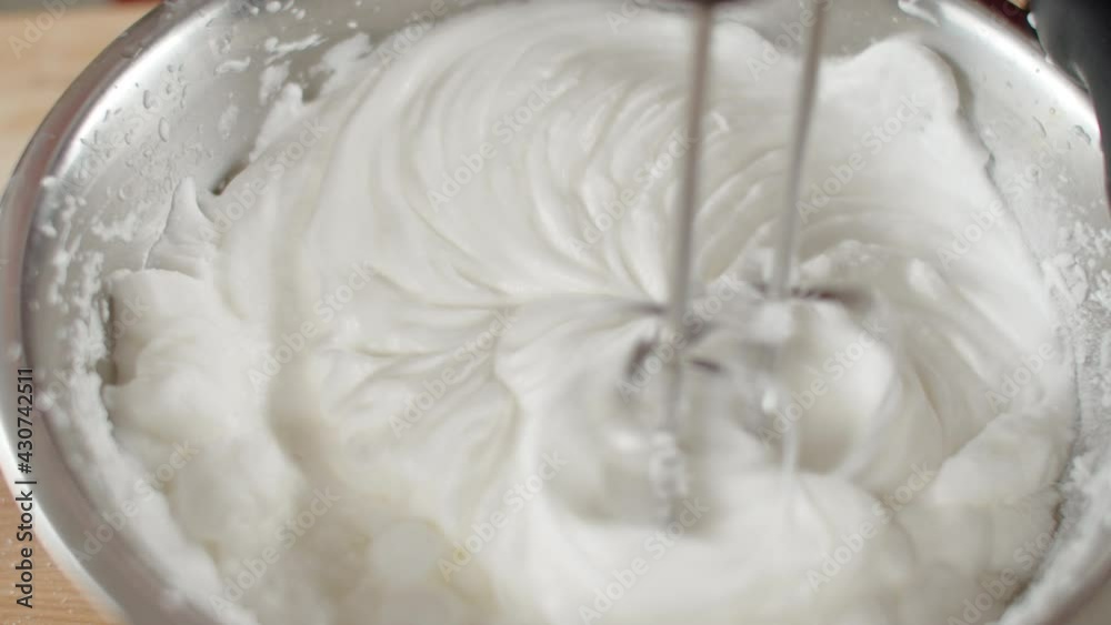 Male chef in black gloves whips egg whites with mixer in iron bowl in restaurant kitchen Male chef in black gloves whips egg whites with mixer in iron bowl in restaurant kitchen