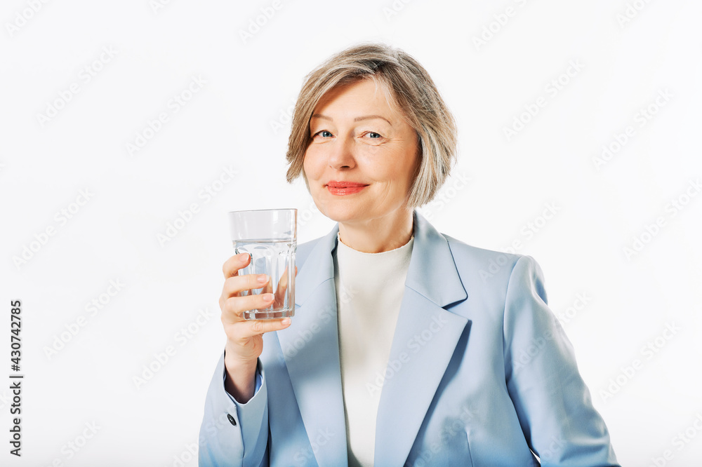 Studio portrait of middle age woman posing on white background, 55 - 60 year old female model holding glass of water Studio portrait of middle age woman posing on white background, 55 - 60 year old female model holding glass of water