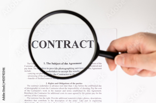 Businessman holding magnifying glass zoom and analyzing contract