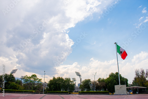Wavy Mexican flag in public square with a cloudy sky as background
