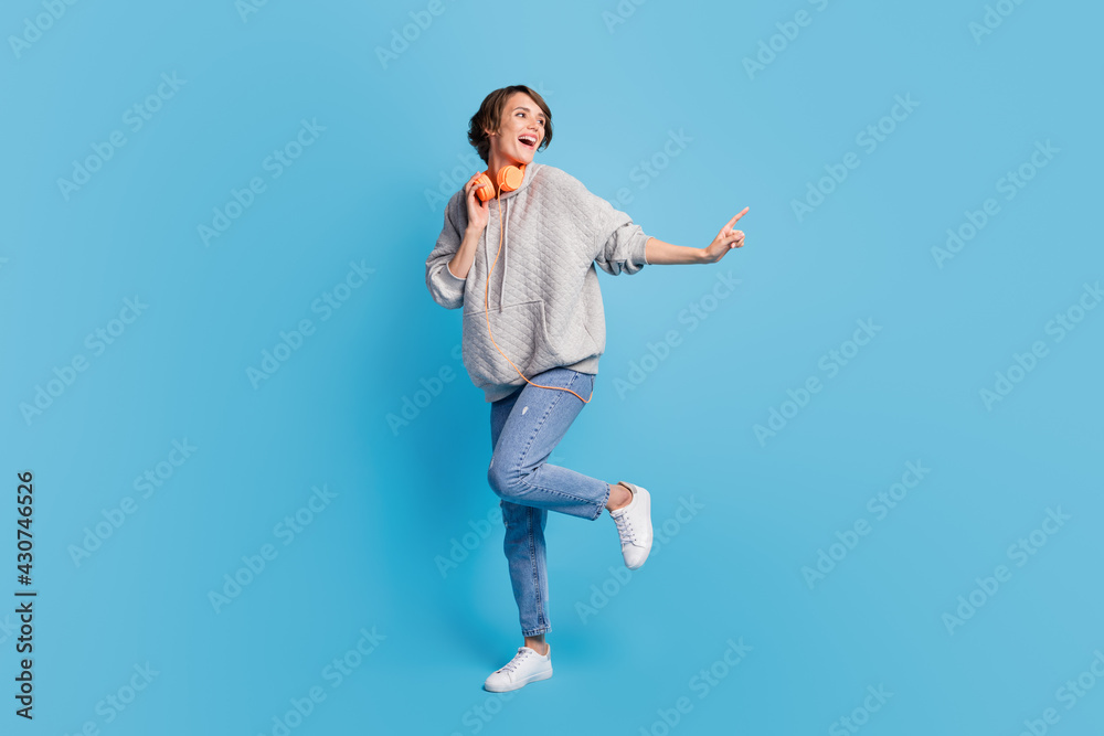 Full length body size view of attractive cheerful girl listening music dancing isolated over bright blue color background