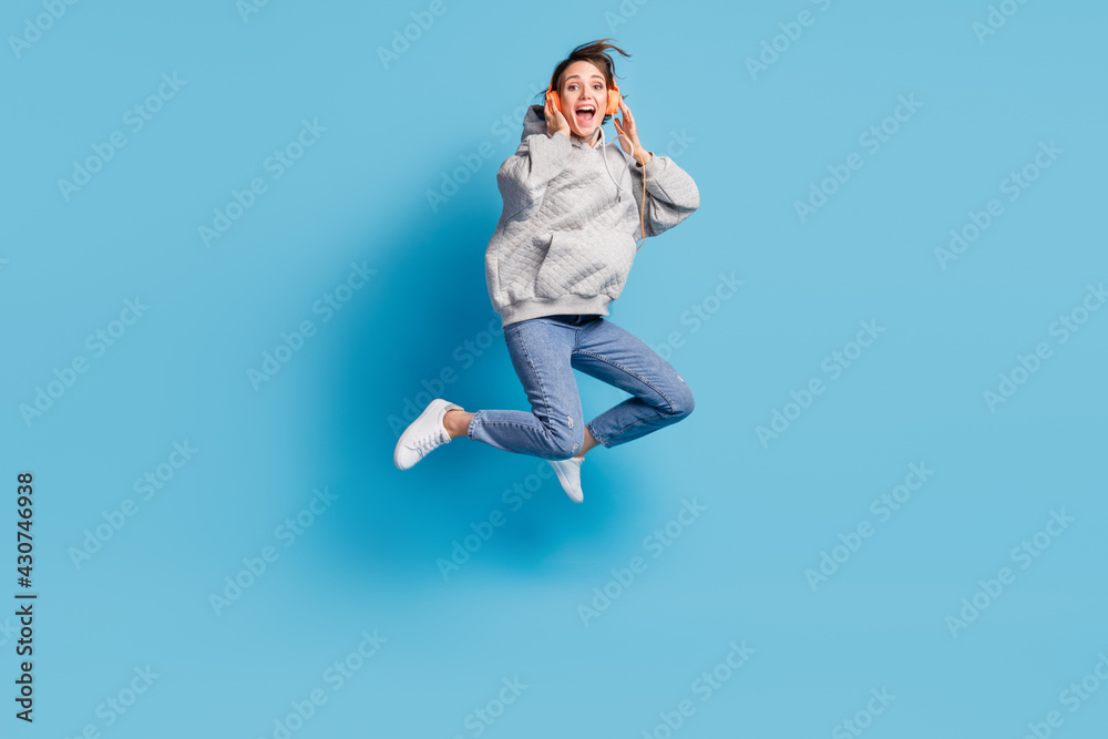 Full length body size view of pretty cheerful crazy girl jumping listening hit having fun isolated over bright blue color background