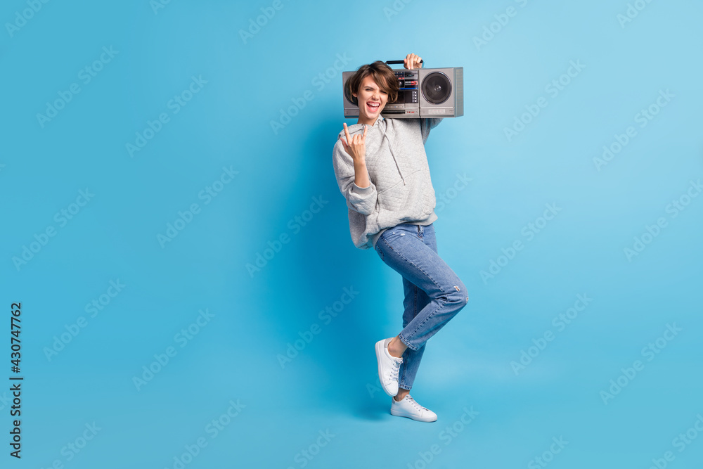 Full length body size photo of funky girl keeping boombox showing heavy metal sign isolated on bright blue color background