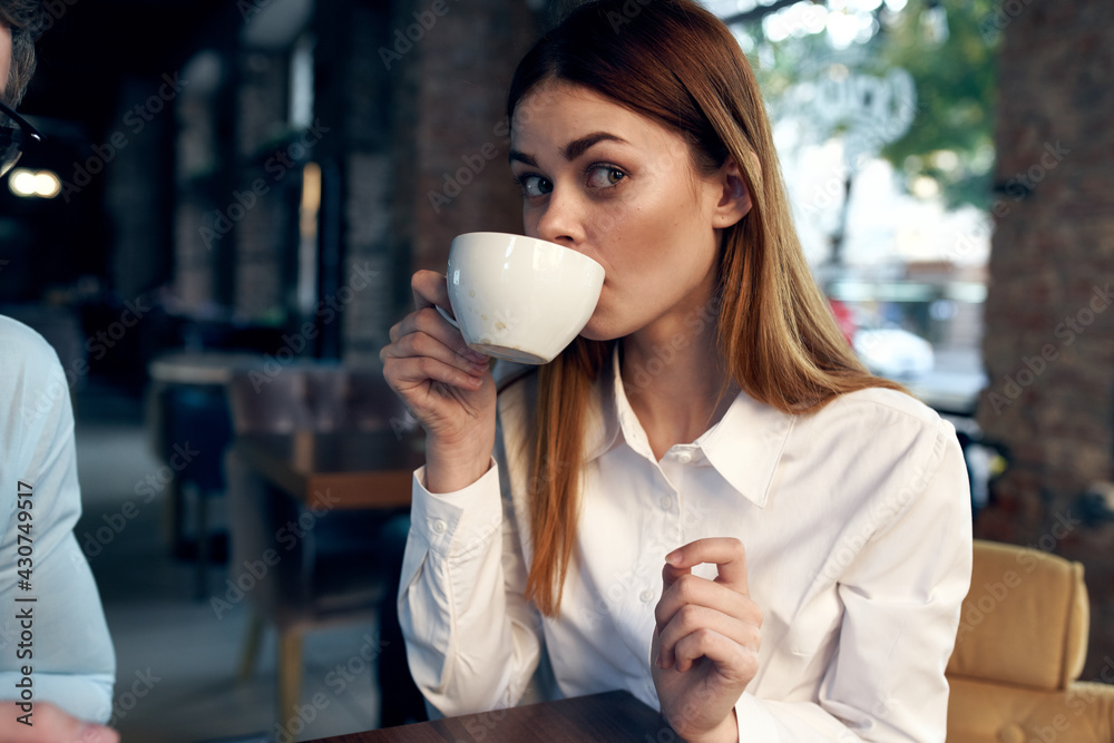 woman drinking coffee at the table next to a man work colleague technology