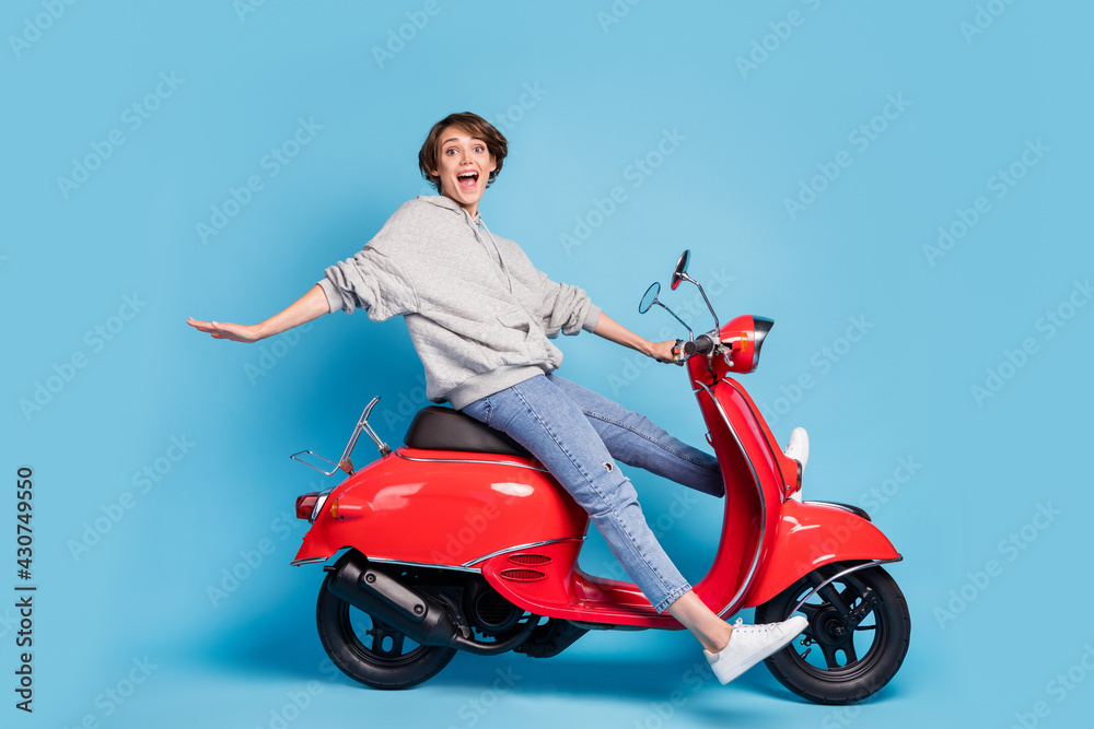 Full length body size photo of funky girl sitting on retro motorbike laughing isolated bright blue color background Full length body size photo of funky girl sitting on retro motorbike laughing isolated bright blue color background