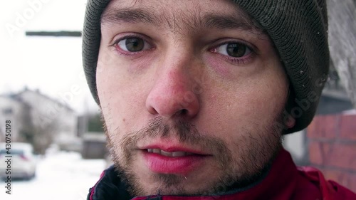 Close up portrait of handsome caucasian man in green winter hat looking into camera lens with serious facial expression.