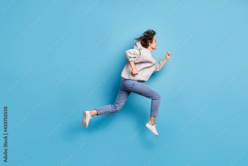 Full length body size side profile photo of girl jumping high running wearing sportswear isolated bright blue color background Full length body size side profile photo of girl jumping high running wearing sportswear isolated bright blue color background