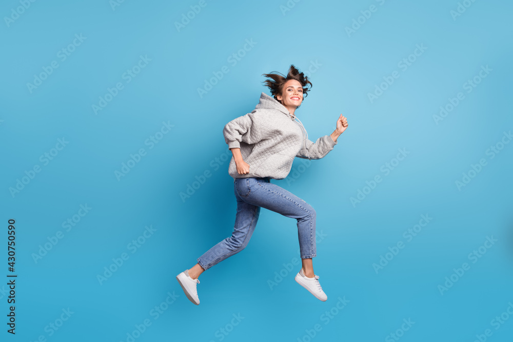 Full length body size view of attractive energetic cheerful girl jumping running fast isolated bright blue color background
